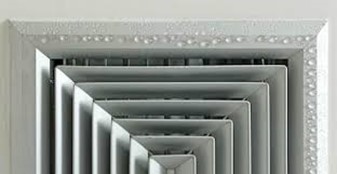 Close-up view of a square ceiling air vent with condensation droplets forming along the edges, indicating moisture accumulation.